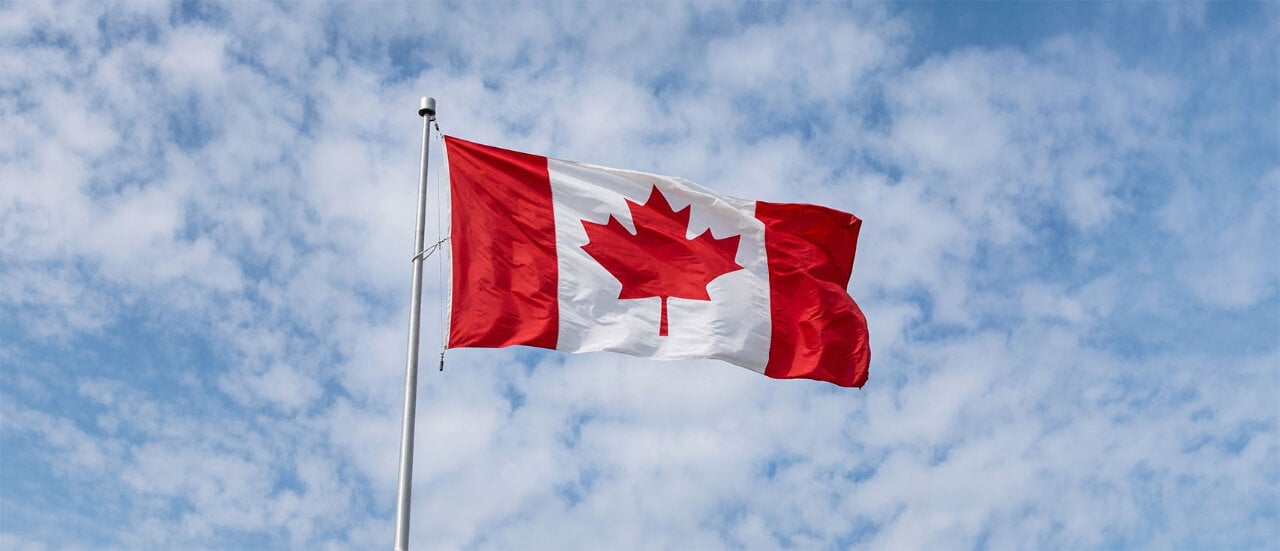 Commercial-grade Canada flag flying on an outdoor flagpole against a blue sky for municipal and Canada Day displays.